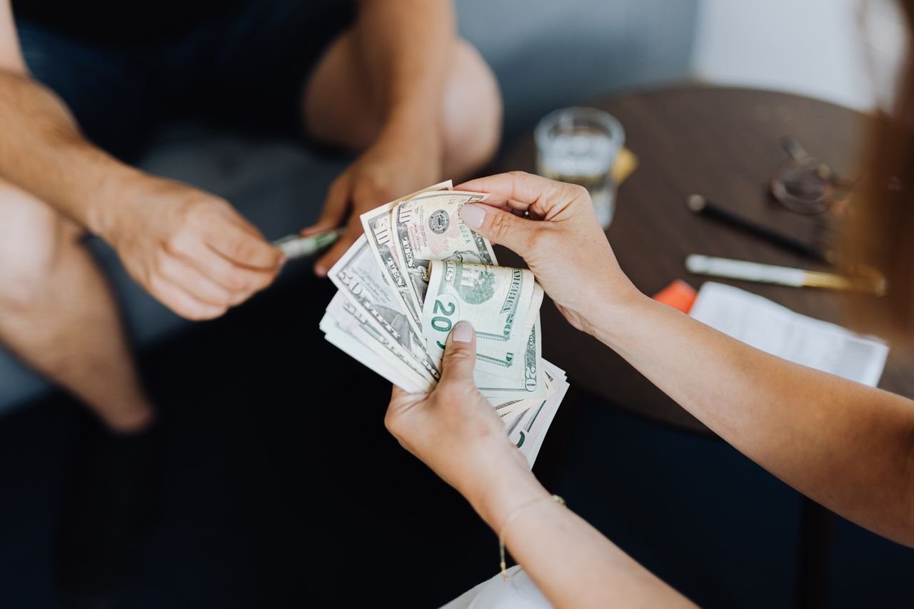 The Art of Drawing Readers In: Your attractive post title goes here Close-up of people handling and counting US dollar bills indoors.